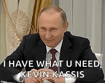 a man in a suit and tie is sitting at a table and smiling while talking to kevin kassis .