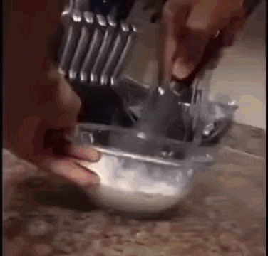 a person is mixing something in a bowl with a knife and spoon .