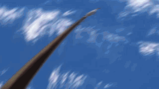 a person is holding a wooden stick in their hand against a blue sky .