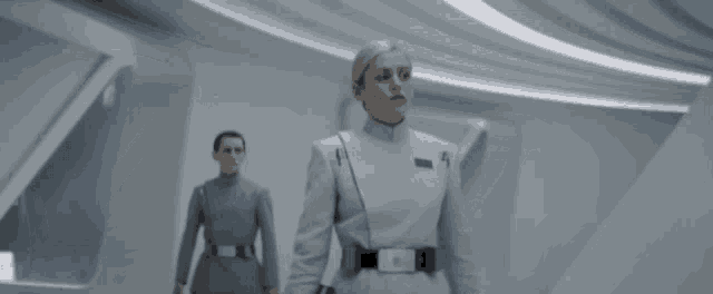 a man and a woman in military uniforms are walking down a hallway .
