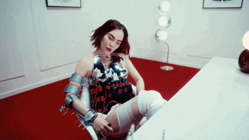 a woman is sitting in a chair with a robotic arm and leg