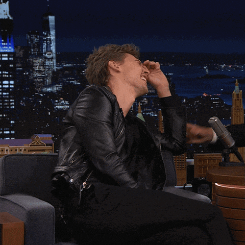 a man in a leather jacket is sitting in front of a microphone