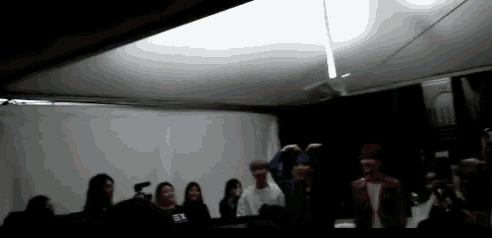 a group of people are gathered in a dark room and one of them is wearing a shirt that says ' ea '