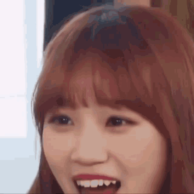 a close up of a woman 's face with her mouth open and a surprised look on her face .