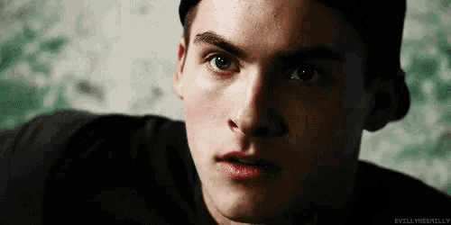 a close up of a young man 's face wearing a hat and a black shirt .