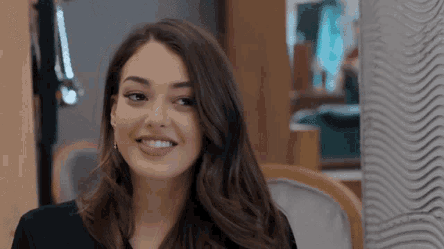 a woman with long dark hair is smiling and wearing a black shirt