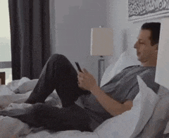 a man is laying on a bed using a cell phone