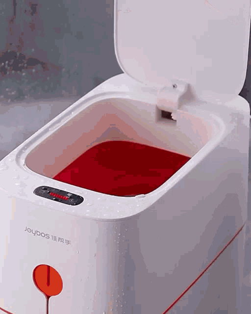 a white joybos trash can has a red liquid in it