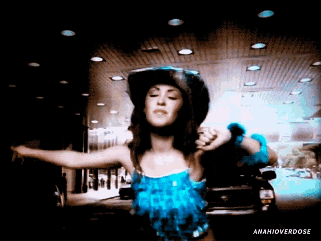 a woman in a blue dress and cowboy hat is dancing in front of a car with the hashtag anahioverdose on the bottom