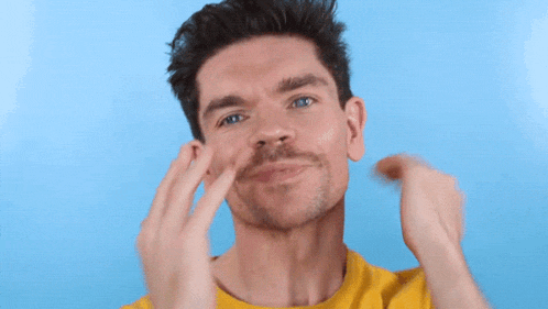 a man in a yellow shirt is holding his hair in his hands