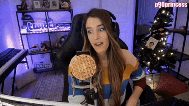 a woman is sitting in front of a microphone with a waffle in front of her and a sign that says twitch