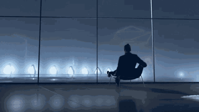 a man sits in a chair in front of a window