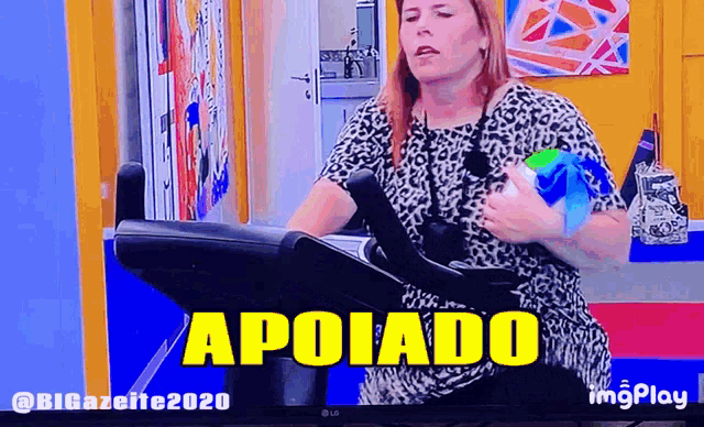a woman is riding an exercise bike with the word apoiado written on the screen