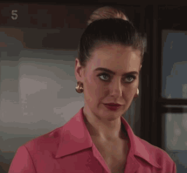 a woman in a pink shirt stands in front of the number 5