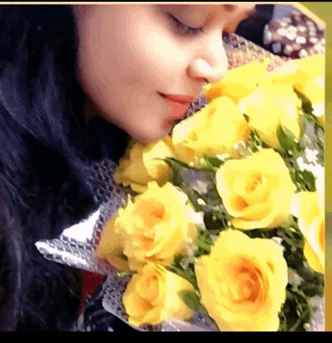 a close up of a woman smelling a bouquet of yellow roses