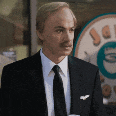 a man in a suit and tie stands in front of a coffee shop