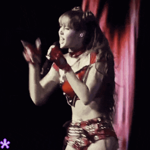 a woman singing into a microphone with a purple star in the corner