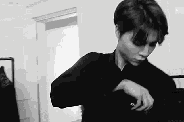 a black and white photo of a man wearing a black shirt .