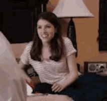 a woman is sitting on a bed with a lamp in the background .