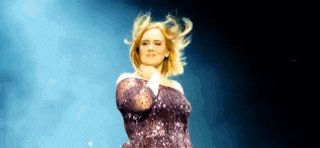 a woman in a purple dress is standing on a stage with her hair blowing in the wind .