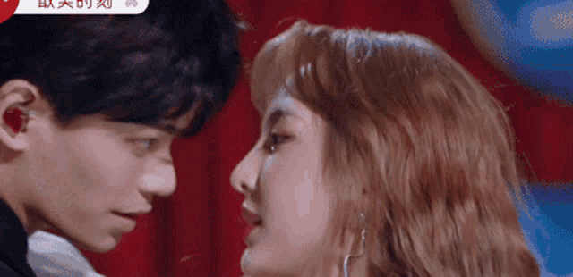 a man and a woman are looking at each other with their eyes closed .