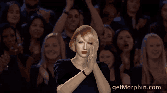 a woman applauds in front of a crowd with the website getmorphin.com in the corner