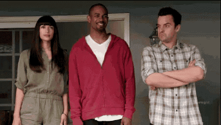 three people are standing next to each other with their arms crossed . one of the men is wearing a pink hoodie .