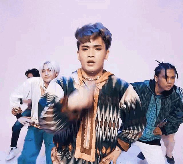 a group of young men are dancing in front of a purple backdrop