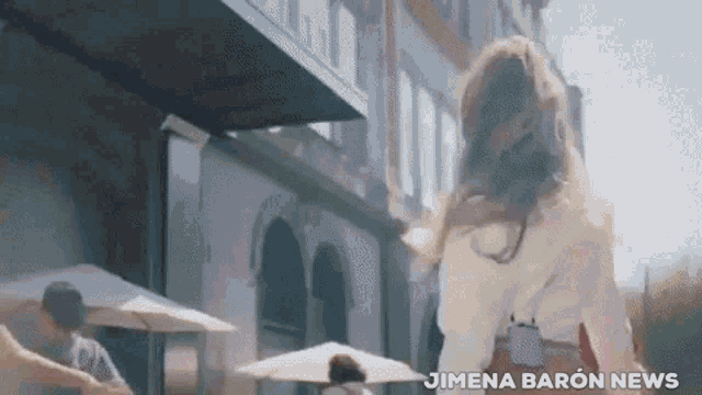 a woman walking in front of a building with the words jimena baron news written below her