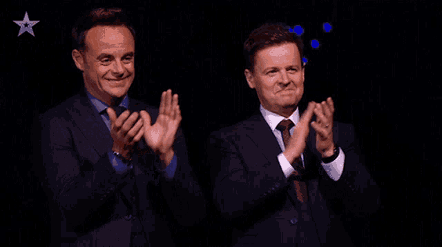 two men in suits and ties are clapping their hands with a star in the background