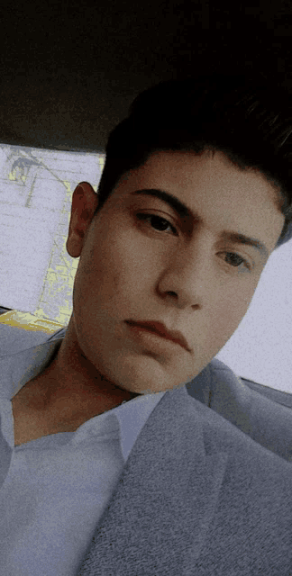 a young man in a suit is sitting in a car and looking at the camera