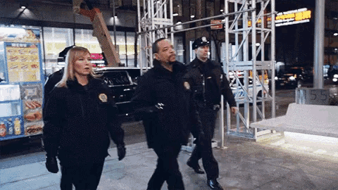 a group of police officers are walking down a street in front of a restaurant