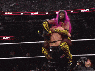 a woman with pink hair is being lifted in a wrestling ring by another woman