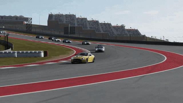 a yellow car is driving on a race track with other cars