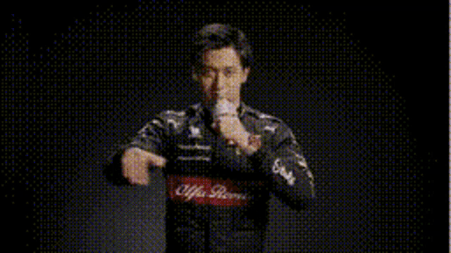a man in a racing suit is holding a microphone and making a funny face .
