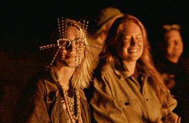 a woman with beads on her face is smiling with another woman
