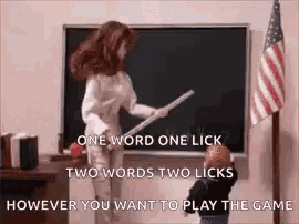 a woman is holding a stick in front of a blackboard while a child licks it .