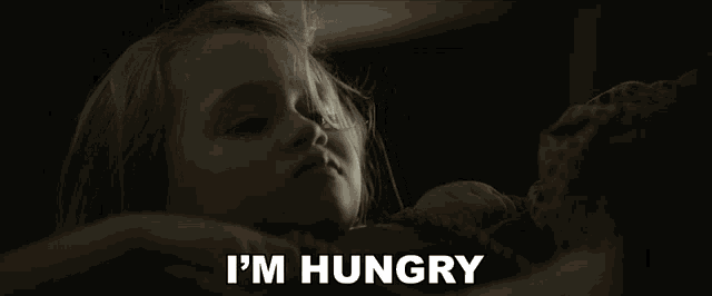 a little girl laying down with the words " i 'm hungry " written above her