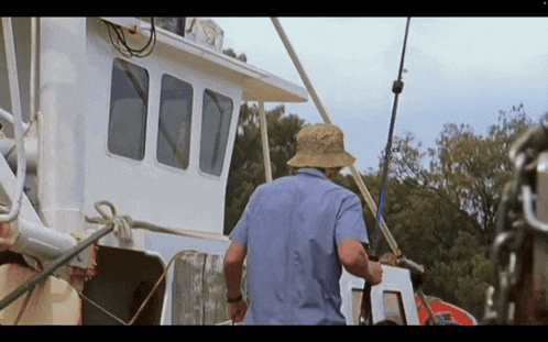 a man wearing a hat and holding a fishing rod stands on a boat