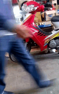 a blurry picture of a person walking past a red motorcycle