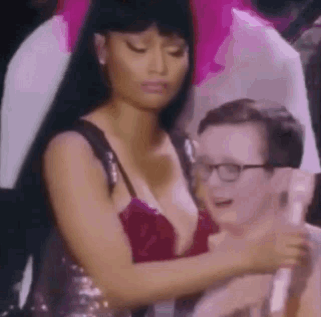 a woman in a plunging red dress is holding a man in a crowd .