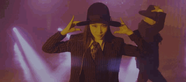 a woman covering her face with her hands while wearing a black hat