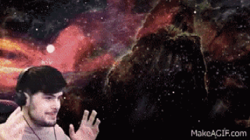 a man wearing headphones stands in front of a galaxy with makeagif.com at the bottom of the screen