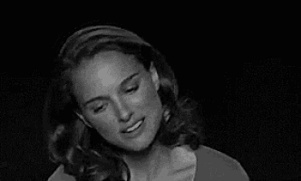 a black and white photo of a woman with long hair smiling in a dark room .