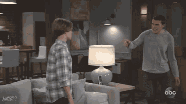 two men are standing in a living room with the abc logo on the bottom