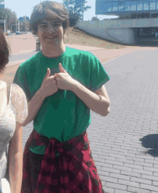 a man in a green shirt is giving a thumbs up sign