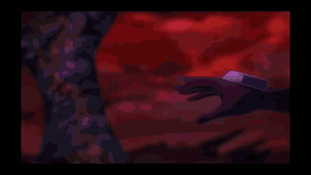 a hand is holding a purple ball in a dark room