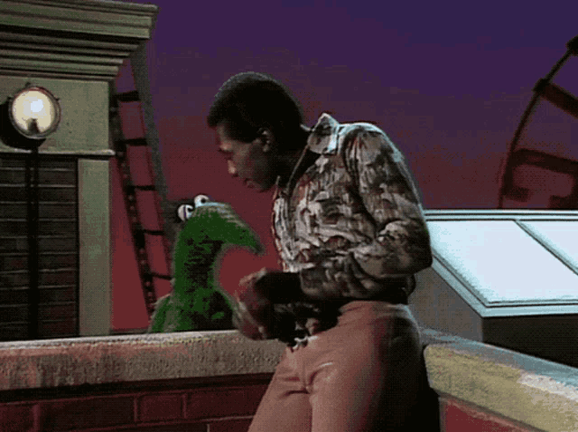 a man standing on a rooftop with a green frog behind him