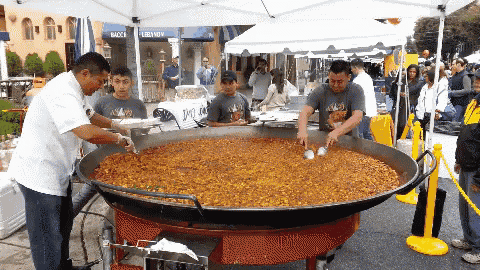 a large pan of food is being cooked in front of a bacca lebanon tent