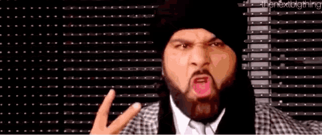 a man with a beard and a hat is making a funny face .